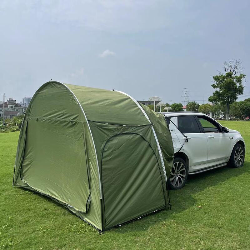 Green vehicle-attached car trunk tent with an integrated canopy, shown set up on a grassy field, highlighting its all-season design and ease of use for car camping and road trips