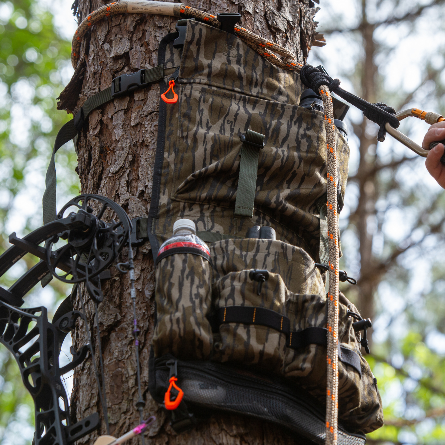 AlphaLife247 Tree Hugger modular hunting pack in BottomLand camo attached to a tree for quiet, organized gear access.